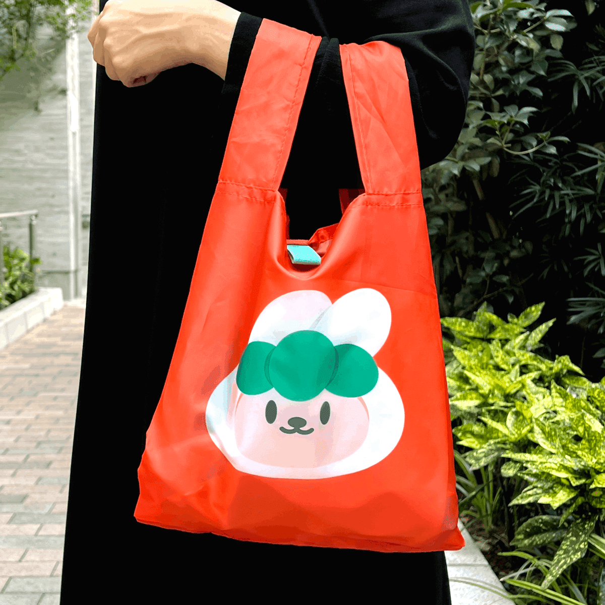 キャロットのオレンジ色のエコバッグを持って歩く様子